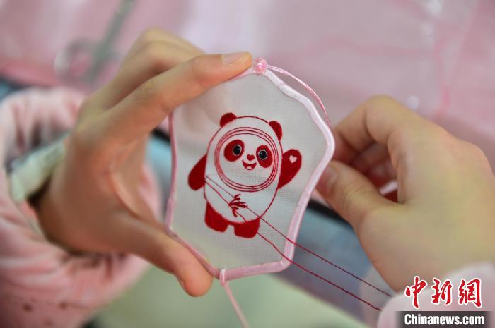 圖為一名小學生正在繡制2022年北京冬奧會吉祥物“冰墩墩”形象。　喻云亮 攝