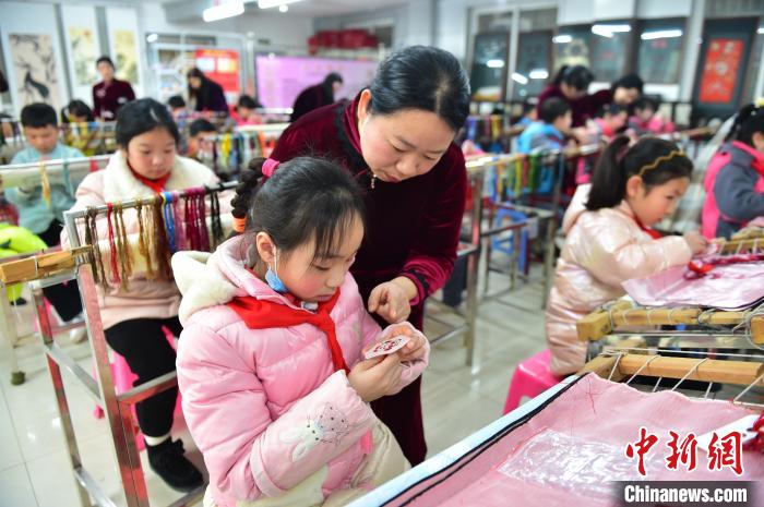 江西省級非遺豫章繡傳承人手把手指導小學生繡制2022年北京冬奧會吉祥物“冰墩墩”形象。　喻云亮 攝