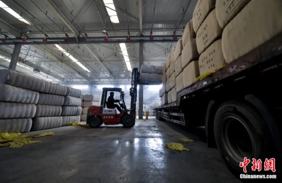新疆喀什綜合保稅區(qū)，喀什啟路國際貿(mào)易有限公司的倉庫內(nèi)，工人正在裝載從塔吉克斯坦和烏茲別克斯坦進(jìn)口的棉花。劉新攝