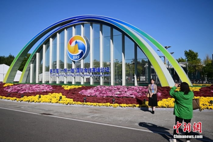 10月15日，北京，工作人員在國家會議中心外的第三屆“一帶一路”國際合作高峰論壇景觀布置前拍照留念。當日，位于國家會議中心的第三屆“一帶一路”國際合作高峰論壇新聞中心啟動試運行。據悉，第三屆“一帶一路”國際合作高峰論壇將于10月17日至18日在北京舉行。<a target='_blank' href='/'><p  align=