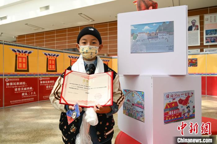 圖為一名獲獎(jiǎng)學(xué)生與自己的繪畫(huà)作品合影。　趙朗 攝