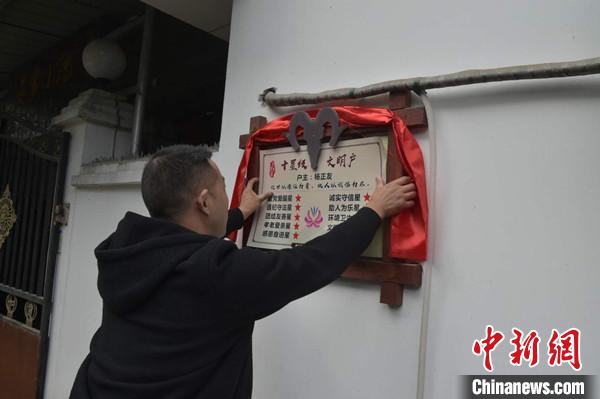 桂溪鎮(zhèn)渭溝村政府工作人員為“十星級(jí)文明戶”掛上牌匾。　楊勇 攝