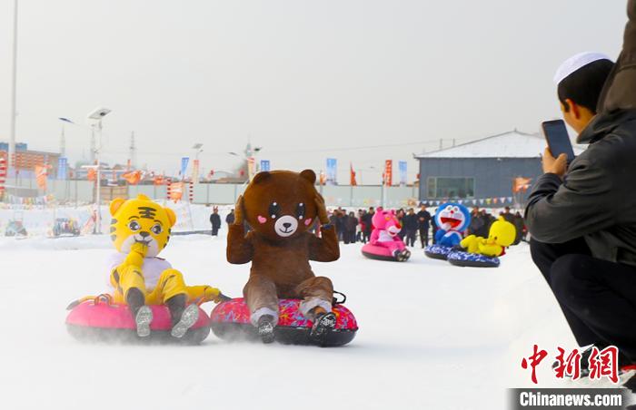 圖為臨夏市南龍鎮馬家莊村舉辦的鄉村文化旅游節上,游客穿著卡通服裝在體驗雪上飛碟項目。近年來,臨夏州形成了“春賞花、夏避暑、秋摘果、冬玩雪”的全季節旅游產品體系。(資料圖) 高展 攝
