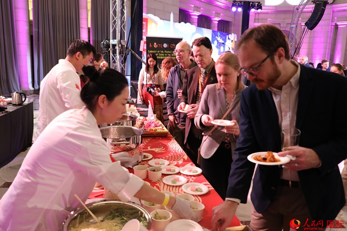 當地時間3月7日晚，華盛頓聯合車站廣場舉行駐美使團“使館主廚挑戰賽”。圖為當地民眾在中國展臺前體驗中國美食。人民網記者 李志偉攝