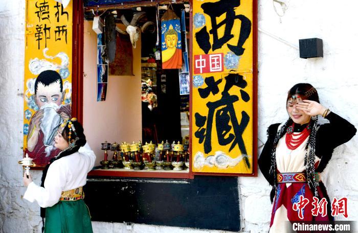 4月17日,游客身著藏式元素服裝在拉薩八廓街拍照留念。 李林 攝