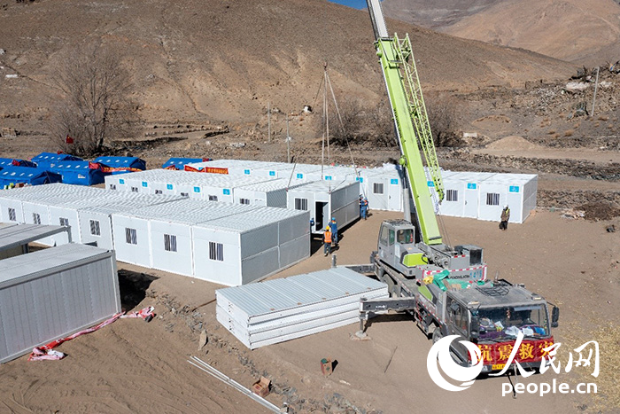 1月9日，在日喀則市定日縣長所鄉古榮村安置點，救援人員和施工人員合力抓緊搭建移動板房，確保受災群眾溫暖過冬。人民網記者 翁奇羽攝